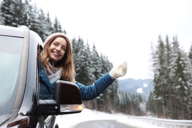 Photo of Young woman driving car and looking out of window on road. Winter vacation