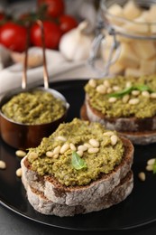 Photo of Tasty bruschettas with pesto sauce and nuts on plate, closeup
