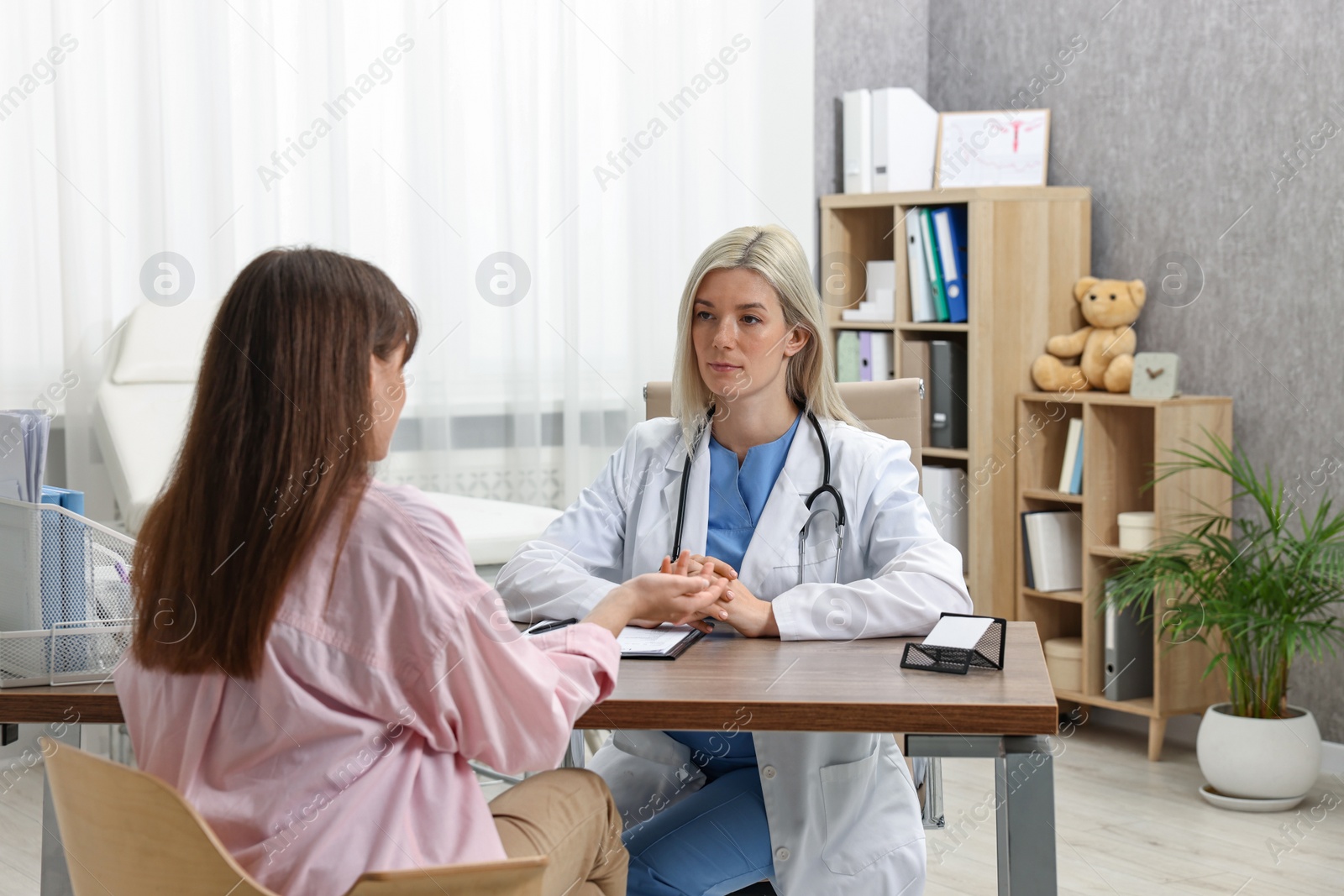 Photo of Doctor consulting pregnant patient at table in clinic