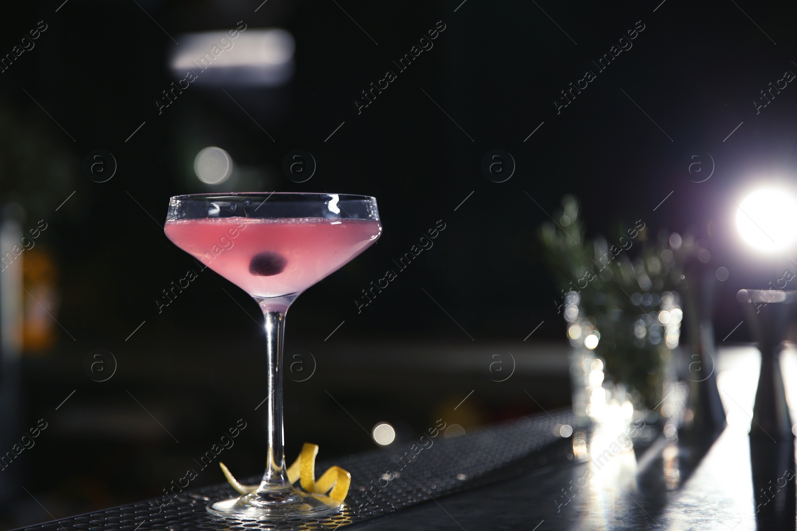 Photo of Glass of cosmopolitan martini cocktail on bar counter. Space for text
