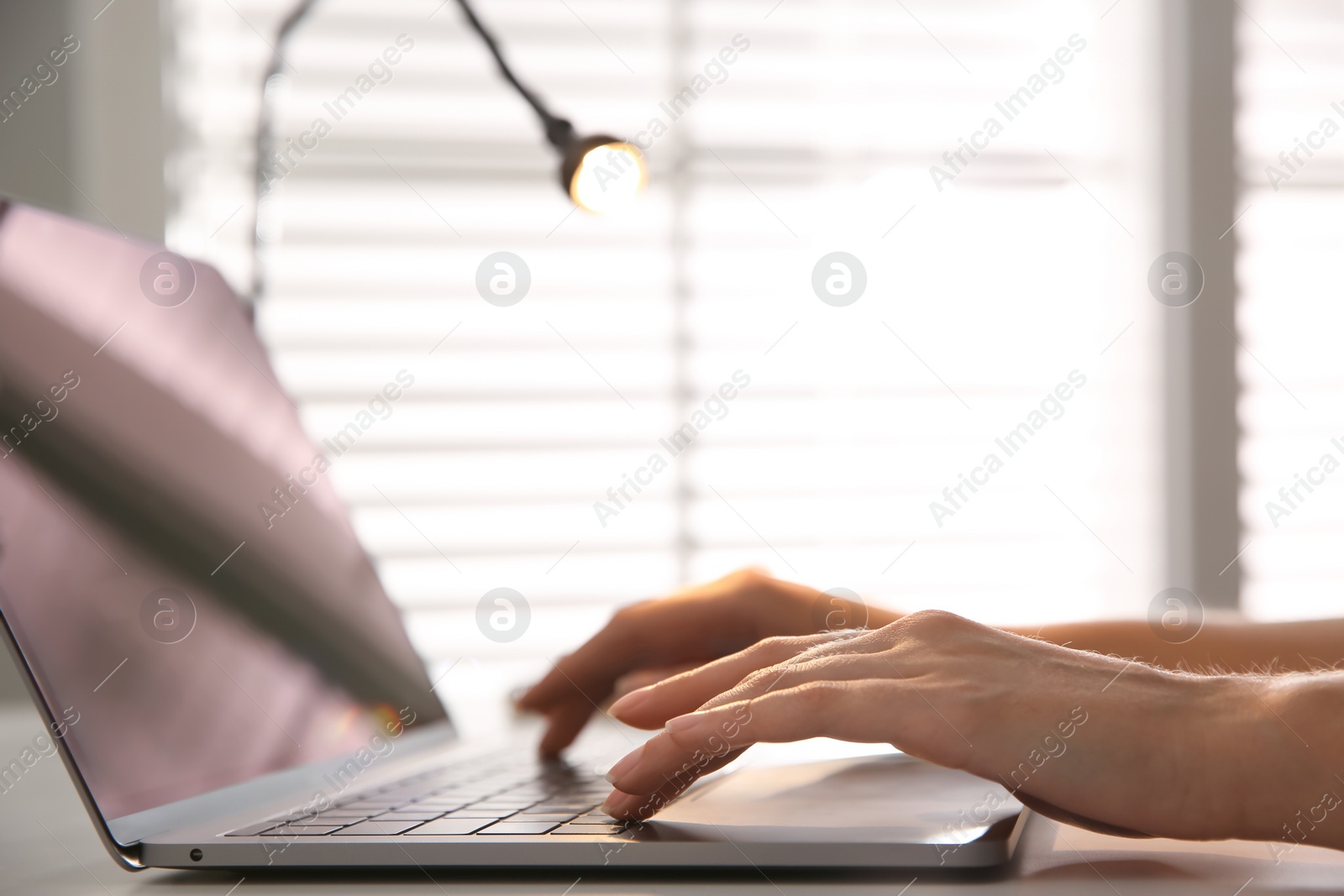 Photo of Woman working with modern laptop at white table, closeup