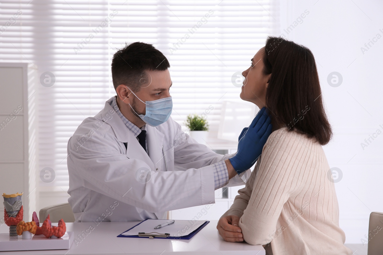 Photo of Doctor examining thyroid gland of patient in hospital