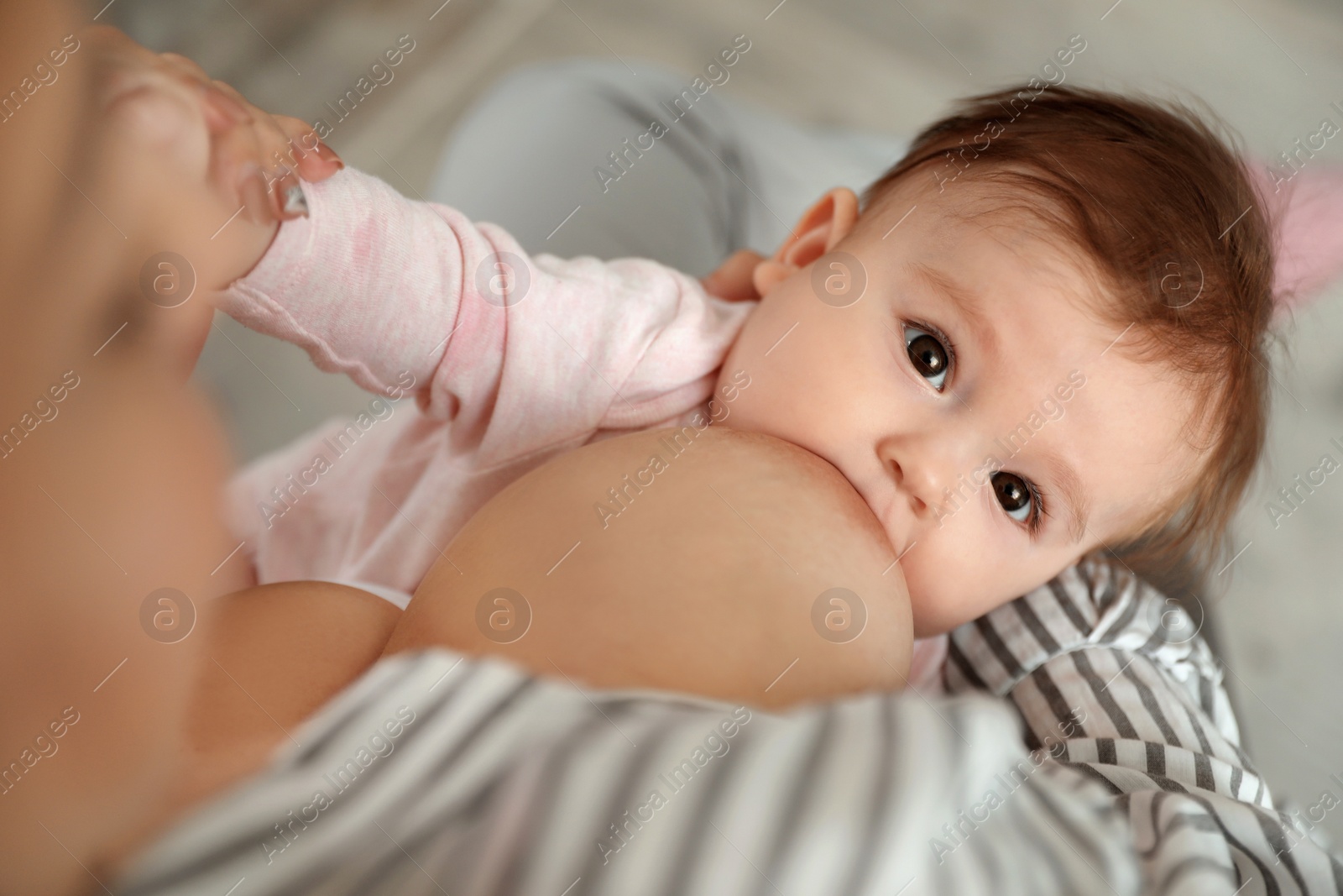 Photo of Young woman breastfeeding her baby at home, closeup