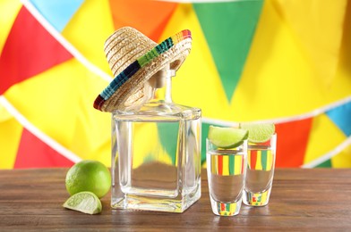 Photo of Mexican sombrero hat, tequila and lime on wooden table