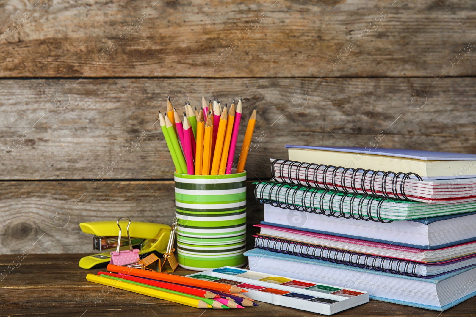 Photo of Different school stationery on table against wooden background