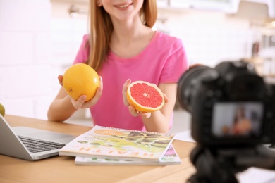 Photo of Cute teenage blogger with fruits recording video at table