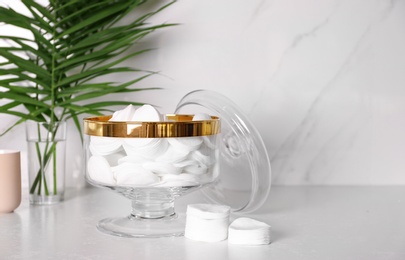 Glass jar with cotton pads on table in bathroom