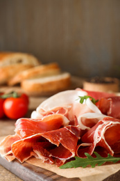 Pile of tasty prosciutto on wooden table