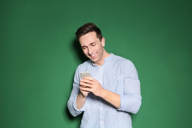 Photo of Portrait of handsome man with mobile phone on color background