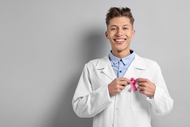 Photo of Mammologist with pink ribbon on light grey background, space for text. Breast cancer awareness