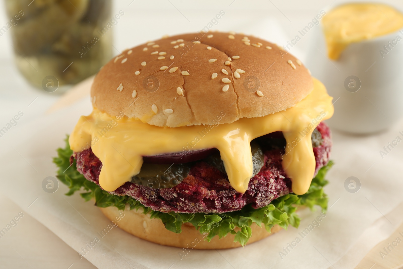 Photo of Tasty vegetarian burger with beet patty on white table, closeup