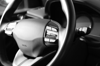 Black steering wheel inside of modern car, closeup