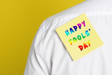 Image of Man with sticker on back against yellow background, closeup. Happy fool's day
