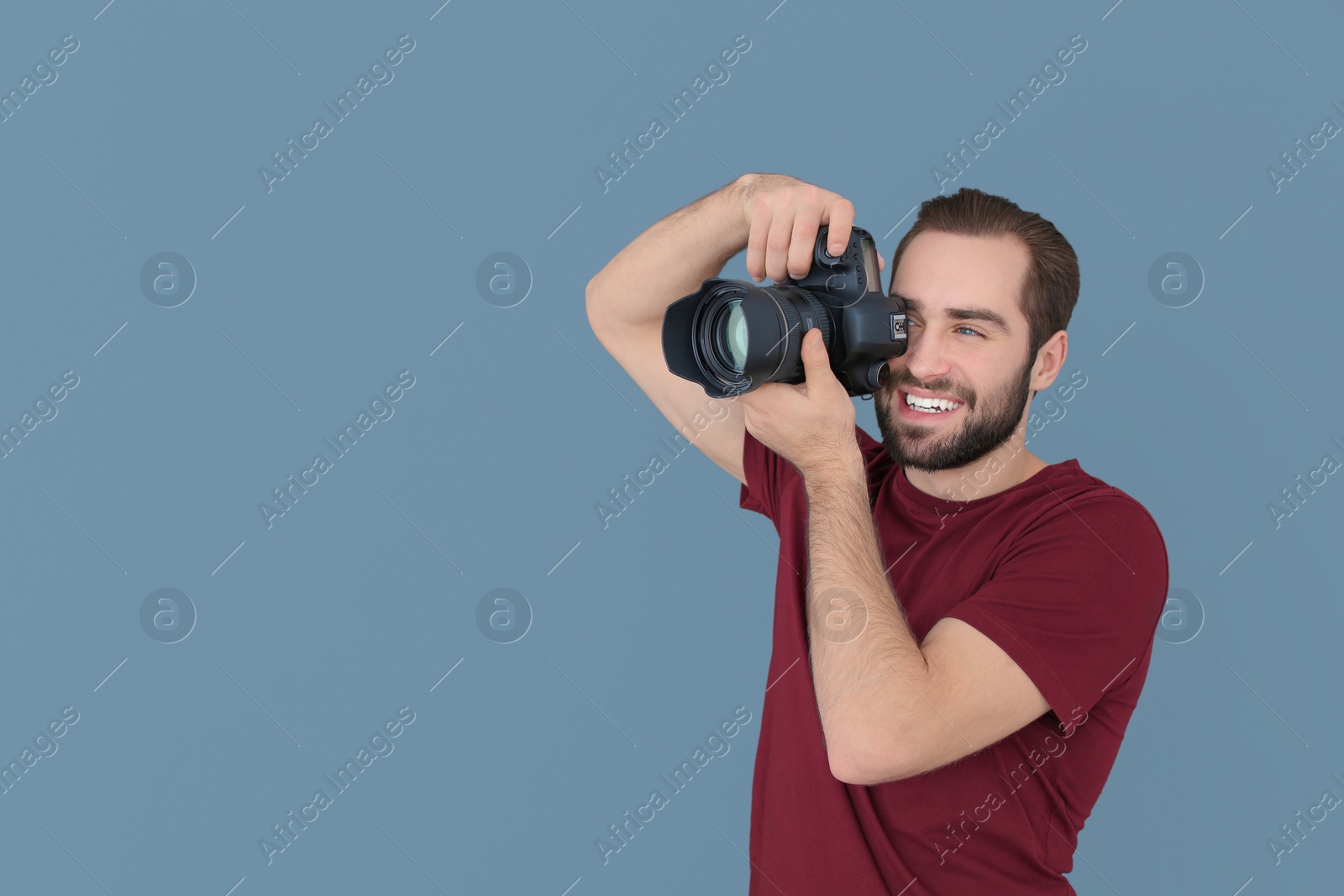 Photo of Young photographer with professional camera on color background