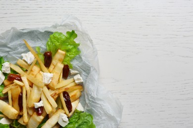 Photo of Delicious parsnip with lettuce, feta cheese and dates on white wooden table, top view. Space for text