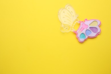 Photo of Decorative cosmetics for kids. Eye shadow palette on yellow background, top view. Space for text