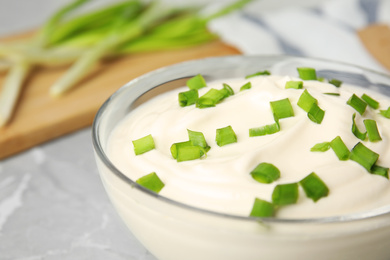 Photo of Fresh sour cream with onion in glass bowl, closeup