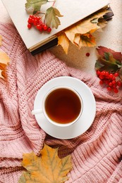 Flat lay composition with cup of aromatic tea and soft pink sweater on beige textured table. Autumn atmosphere