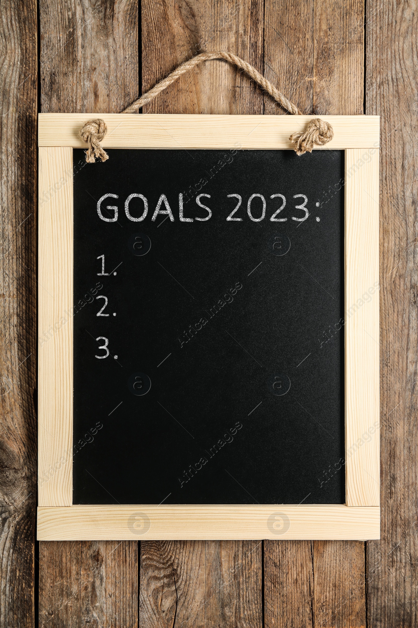 Image of Blackboard with phrase GOALS 2023 and empty checklist on hanging on wooden background