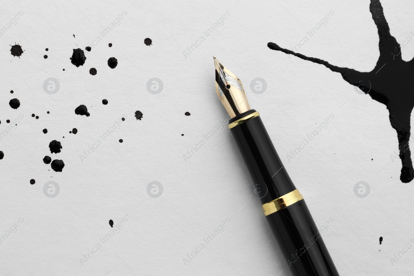 Photo of Stylish fountain pen on paper with blots of ink, top view