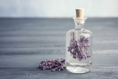 Natural herbal oil and lavender flowers on wooden table. Space for text