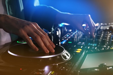 Photo of DJ creating music on modern console mixer in night club, closeup