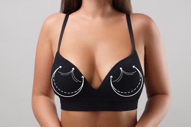 Image of Breast surgery. Woman with markings on bra against light background, closeup