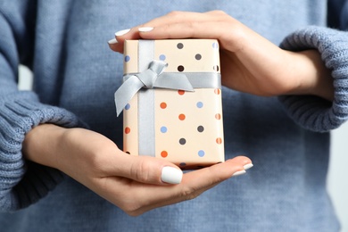 Photo of Woman in warm sweater holding Christmas gift, closeup view