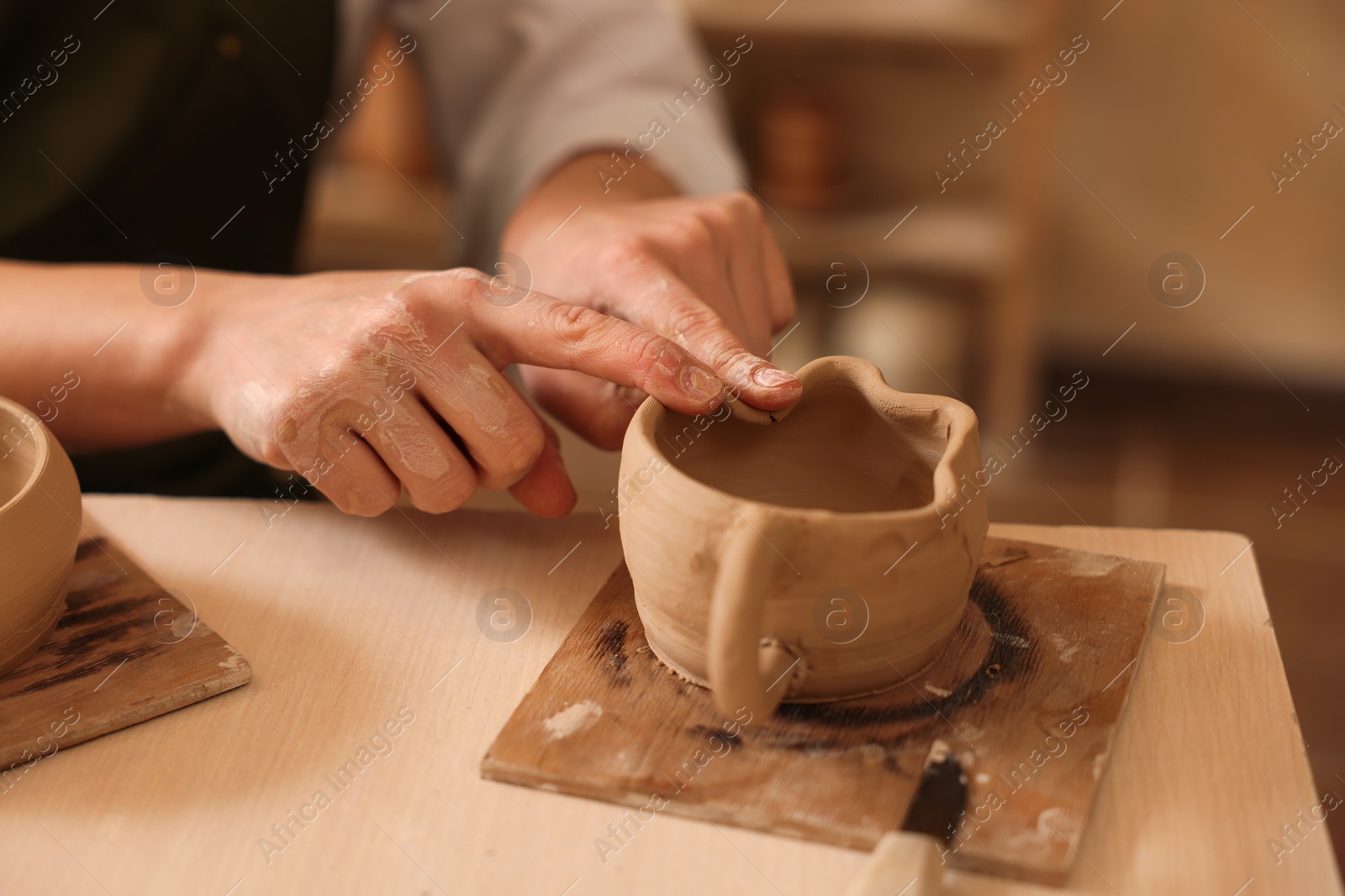 Photo of Pottery crafting. Woman sculpting with clay at table indoors, closeup