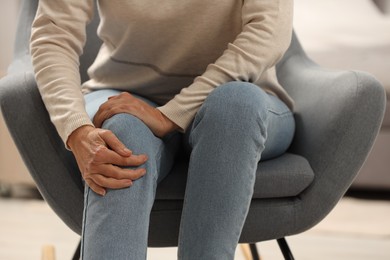 Photo of Mature woman suffering from knee pain indoors, closeup. Rheumatism symptom