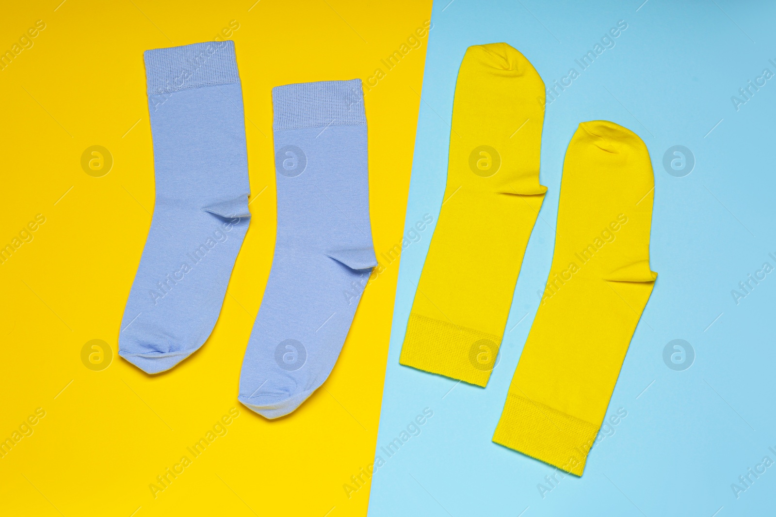 Photo of Blue and yellow socks on color background, flat lay