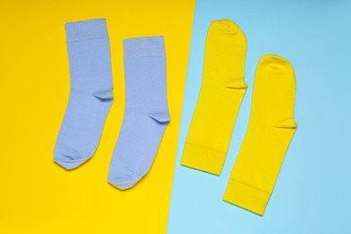 Blue and yellow socks on color background, flat lay