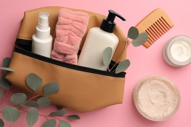 Preparation for spa. Compact toiletry bag with different cosmetic products, comb and eucalyptus on pink background, flat lay