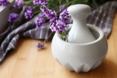 Photo of Mortar with fresh lavender flowers and pestle on wooden table, closeup. Space for text