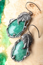 Photo of Beautiful pair of silver earrings with amazonite gemstones on textured surface, closeup