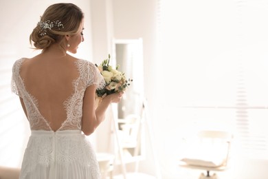 Photo of Gorgeous bride in beautiful wedding dress holding bouquet in room. Space for text