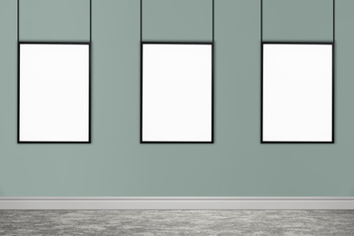 Image of Frames with empty canvases on grey wall in modern art gallery. Space for design