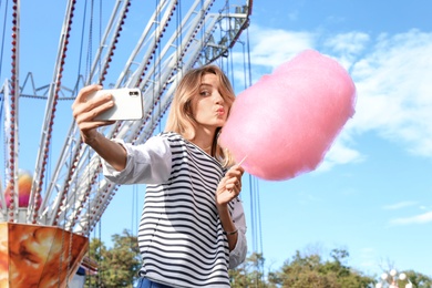 Photo of Attractive woman taking selfie with cotton candy in amusement park