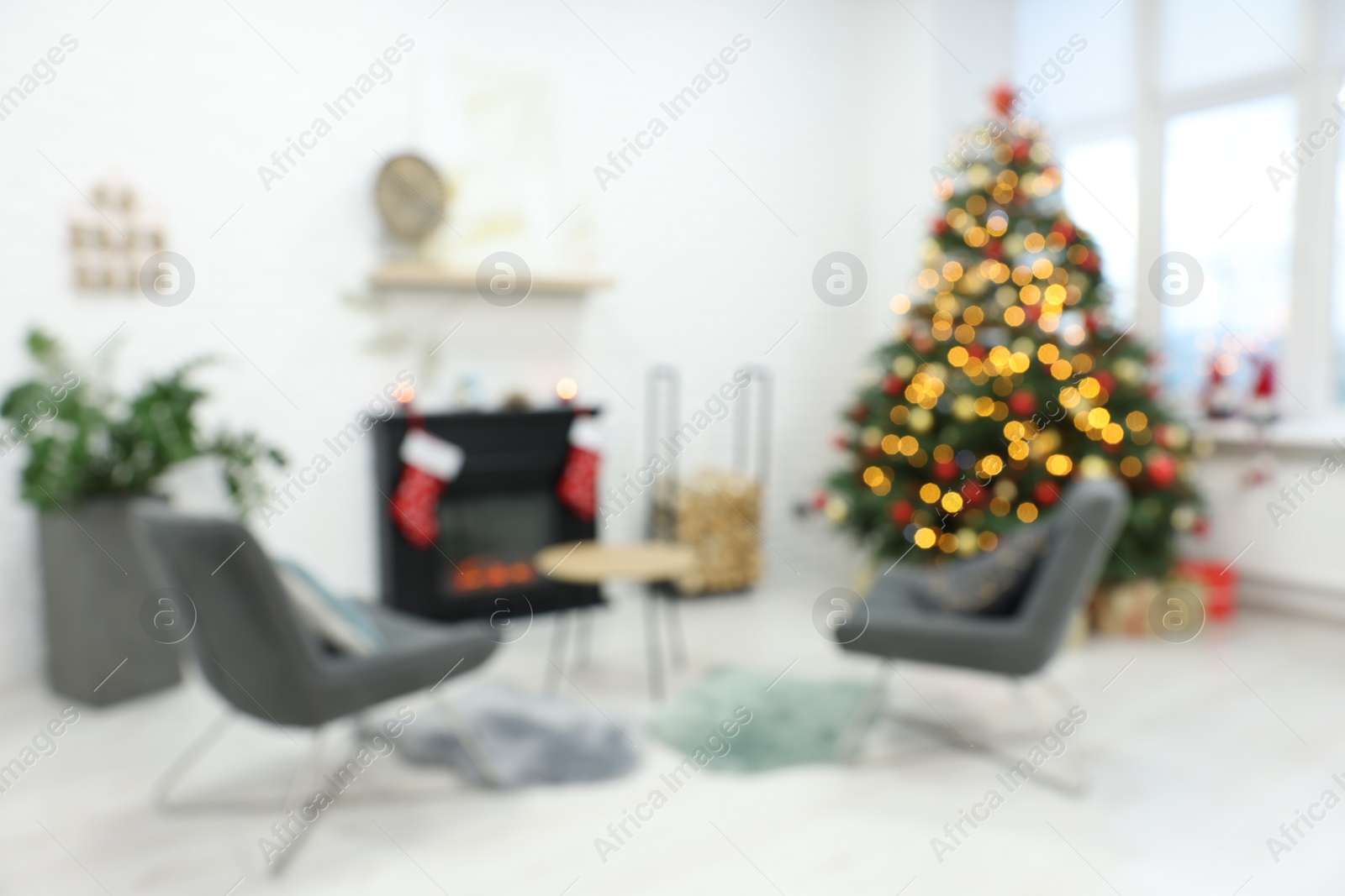 Photo of Beautiful Christmas tree near fireplace and cosy armchairs in room, blurred view