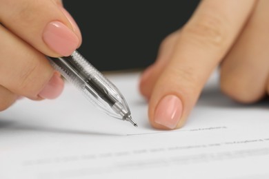 Woman signing document with pen, closeup view