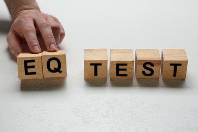 Man taking cubes with text IQ Test on light background, closeup
