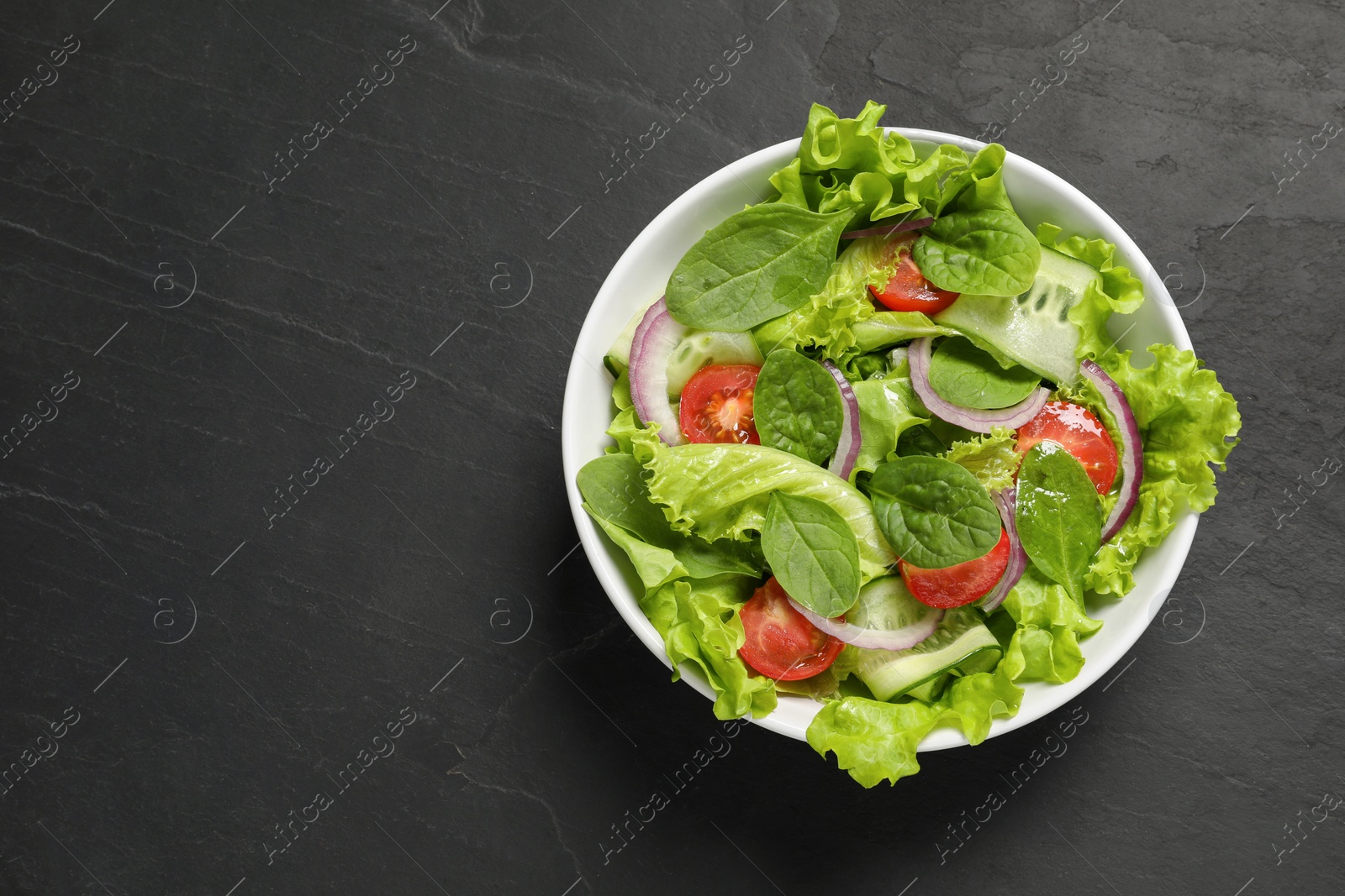 Photo of Delicious vegetable salad on grey table, top view. Space for text