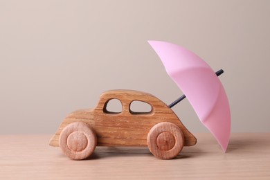 Photo of Small umbrella and toy car on wooden table