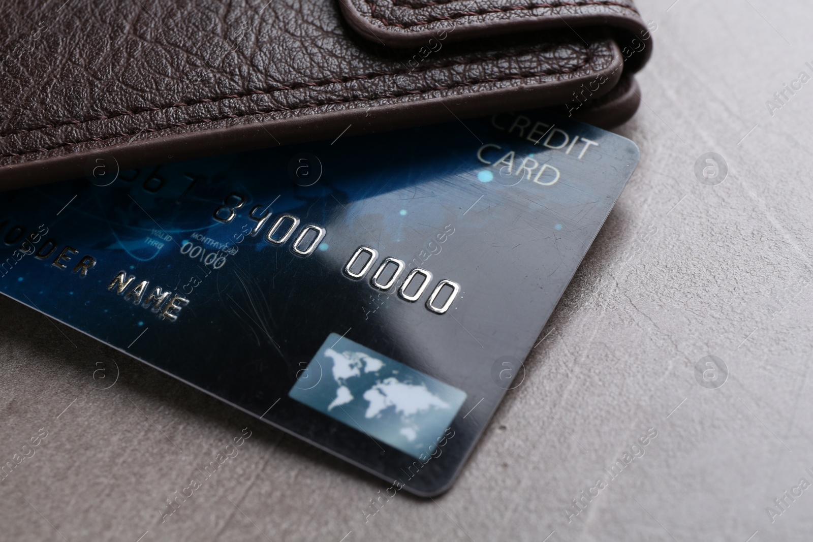 Photo of Credit card and leather wallet on grey textured table, closeup