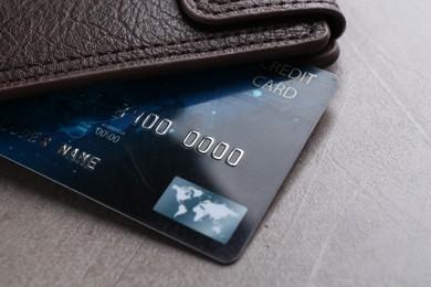 Credit card and leather wallet on grey textured table, closeup