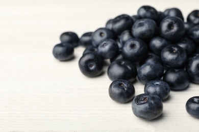 Photo of Fresh acai berries on white wooden table, closeup view. Space for text