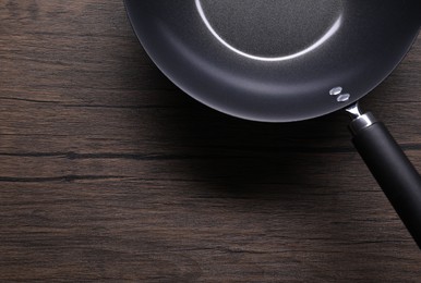 Empty iron wok on wooden table, top view. Space for text