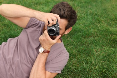 Photo of Man with camera taking photo on green grass, space for text. Interesting hobby