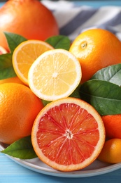 Different citrus fruits on light blue wooden table, closeup