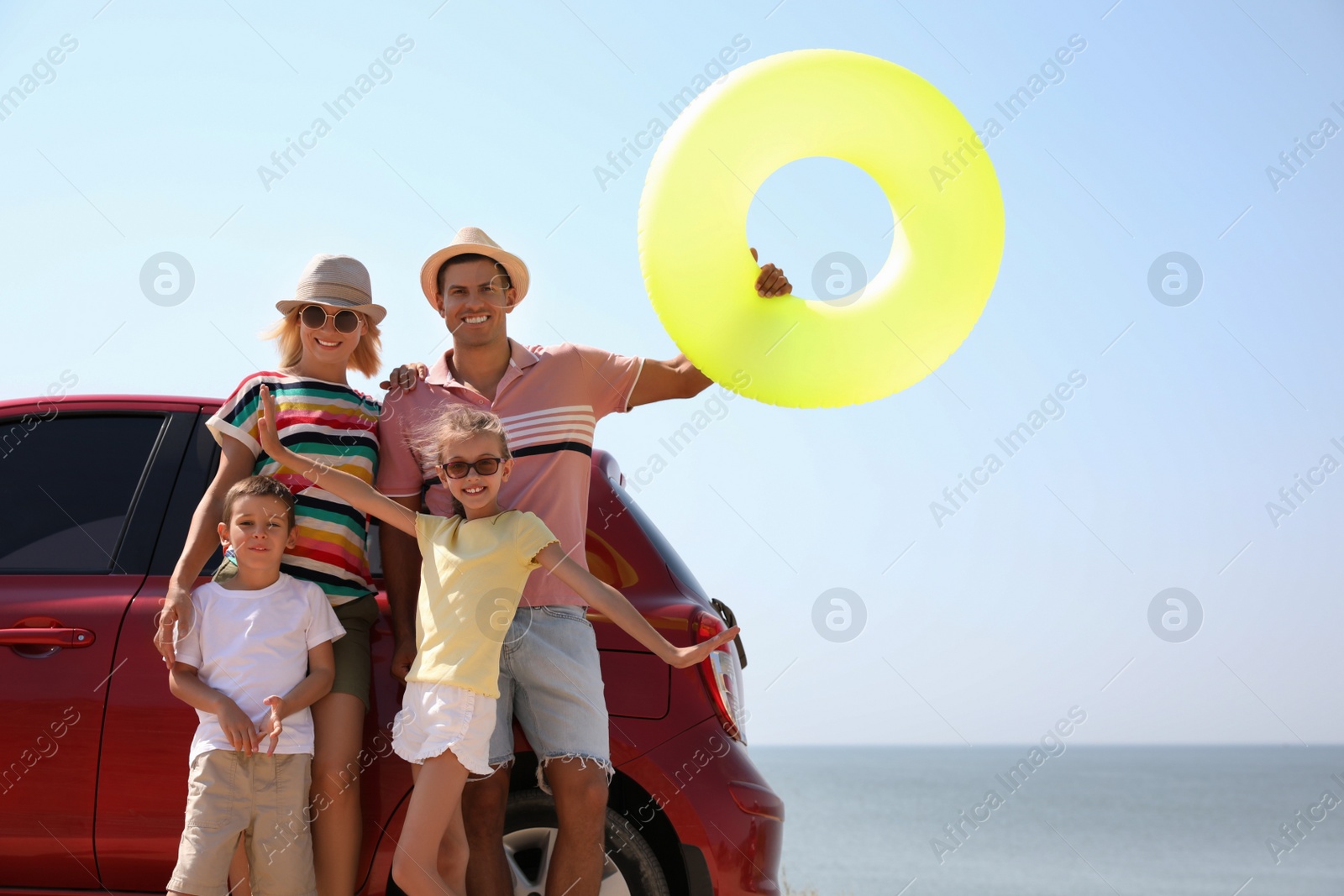 Photo of Happy family with inflatable ring near car at beach